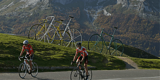 Men on bicycles with mountains and 3 bikes in background